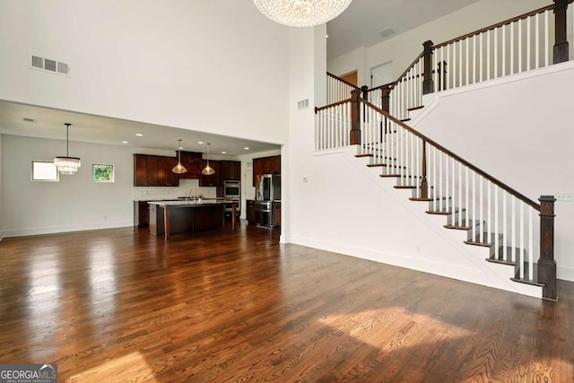 847 Rolling Hl, Kennesaw, GA 30152 - unfurnished living room featuring a chandelier, dark wood-style floors, a high ceiling, stairway, and a sink