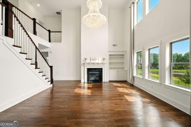 847 Rolling Hl, Kennesaw, GA 30152 - unfurnished living room featuring a towering ceiling, a chandelier, a fireplace with flush hearth, wood finished floors, and baseboards