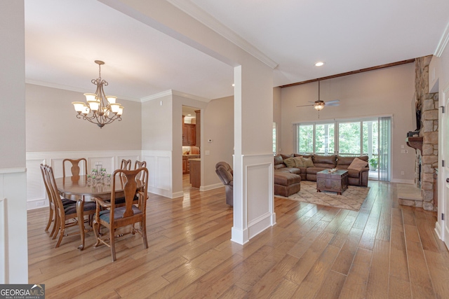 319 Beaconsfield Dr, Sharpsburg, GA 30277 - dining room featuring crown molding, light wood-style flooring, a wainscoted wall, a stone fireplace, and a chandelier