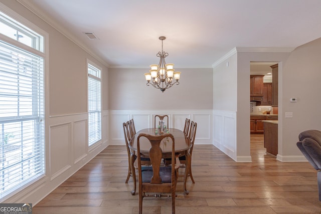 319 Beaconsfield Dr, Sharpsburg, GA 30277 - dining area featuring a chandelier, light wood finished floors, a wainscoted wall, crown molding, and a decorative wall