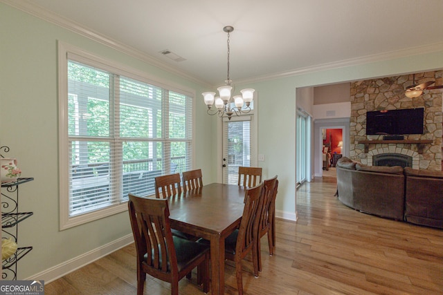 319 Beaconsfield Dr, Sharpsburg, GA 30277 - dining area with a chandelier, ornamental molding, a stone fireplace, light wood-style floors, and baseboards