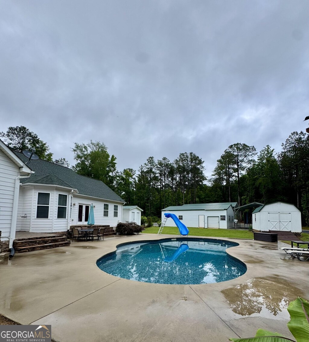 4288 Ga Highway 16 W, Monticello, GA 31064 - swimming pool with a water slide, a patio, and view of wooded area