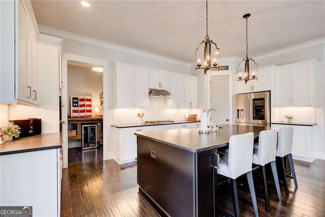 164 Inwood Walk, Woodstock, GA 30188 - kitchen featuring appliances with stainless steel finishes, under cabinet range hood, a chandelier, beverage cooler, and a kitchen island with sink