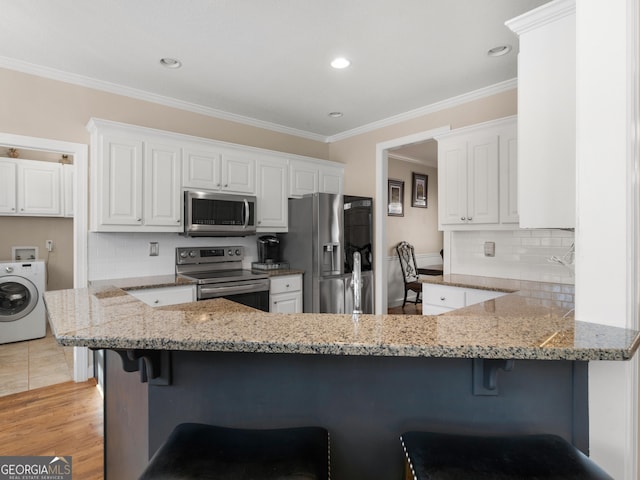 355 Parker Rd, Covington, GA 30014 - kitchen featuring stainless steel appliances, washer / clothes dryer, a peninsula, light stone countertops, and decorative backsplash