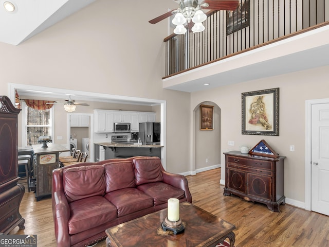 355 Parker Rd, Covington, GA 30014 - living area with ceiling fan, high vaulted ceiling, washing machine and dryer, arched walkways, and light wood-type flooring