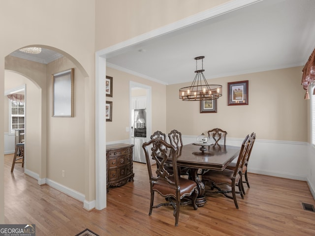 355 Parker Rd, Covington, GA 30014 - dining room with arched walkways, light wood finished floors, ornamental molding, and a chandelier