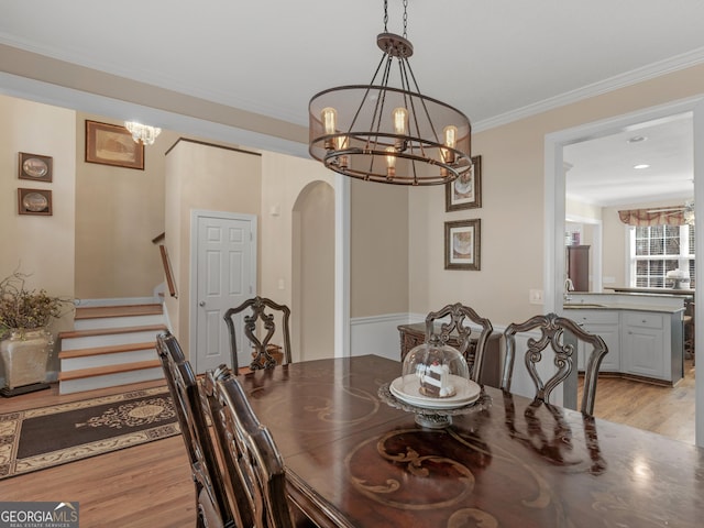 355 Parker Rd, Covington, GA 30014 - dining room with a chandelier, light wood finished floors, arched walkways, ornamental molding, and stairs