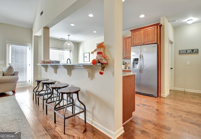 149 Horizon Hl, Newnan, GA 30265 - kitchen featuring stainless steel fridge with ice dispenser, a breakfast bar, brown cabinets, baseboards, and recessed lighting
