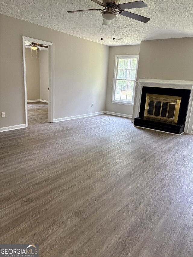 6103 Chaseland Rd, Rex, GA 30273 - unfurnished living room with a textured ceiling, a ceiling fan, wood finished floors, a glass covered fireplace, and baseboards
