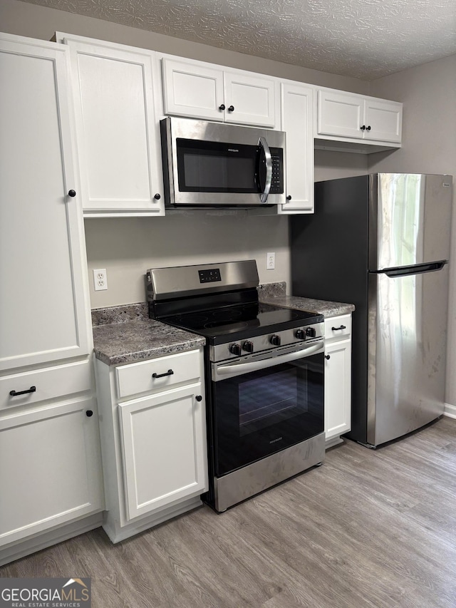 6103 Chaseland Rd, Rex, GA 30273 - kitchen with appliances with stainless steel finishes, light wood finished floors, white cabinets, and a textured ceiling