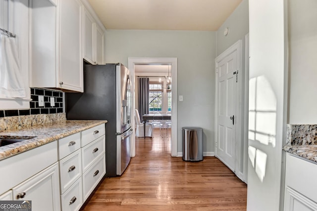 570 Southview Dr, Athens, GA 30605 - kitchen featuring light wood finished floors, decorative backsplash, white cabinets, stainless steel refrigerator with ice dispenser, and light stone counters