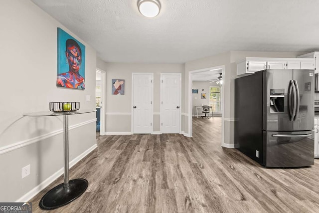 135 Dunwick Ln, Mcdonough, GA 30253 - kitchen with stainless steel fridge, white cabinetry, baseboards, wood finished floors, and a textured ceiling
