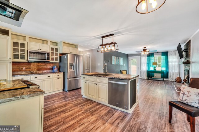 113 Fletcher Rd, Eatonton, GA 31024 - kitchen featuring appliances with stainless steel finishes, cream cabinetry, wood finished floors, dark stone counters, and open floor plan