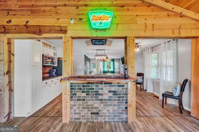 113 Fletcher Rd, Eatonton, GA 31024 - kitchen featuring stainless steel microwave, white cabinetry, light wood-style flooring, beamed ceiling, and a sink