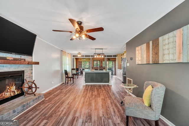 113 Fletcher Rd, Eatonton, GA 31024 - living area with wood finished floors, a fireplace, a ceiling fan, and crown molding