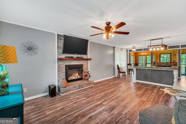 113 Fletcher Rd, Eatonton, GA 31024 - living area featuring ceiling fan, wood finished floors, baseboards, a brick fireplace, and ornamental molding