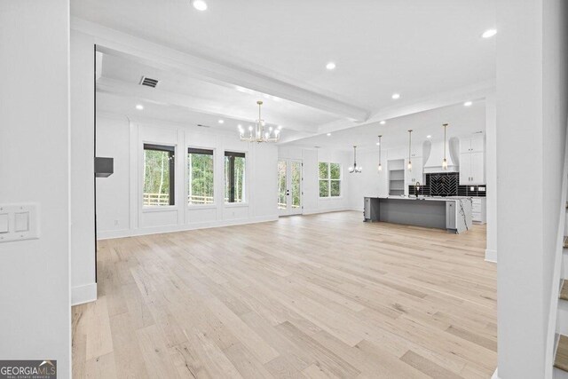 1387 Mineral Springs Rd, Hoschton, GA 30548 - unfurnished living room with a chandelier, recessed lighting, light wood-style floors, beamed ceiling, and baseboards