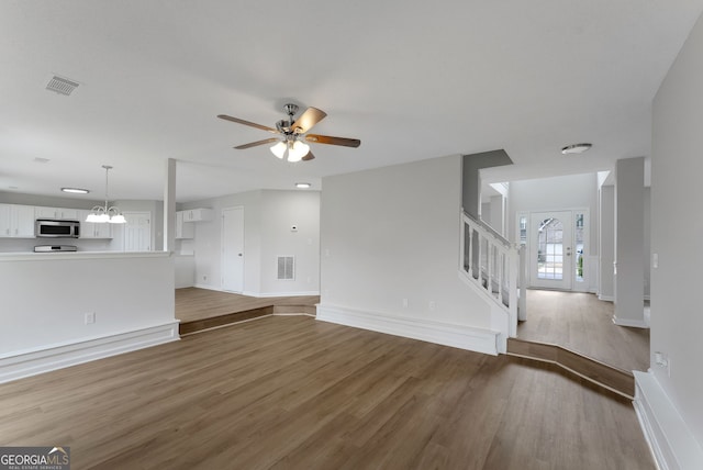 907 Brisley Cir, Hampton, GA 30228 - unfurnished living room with wood finished floors, stairway, and a ceiling fan