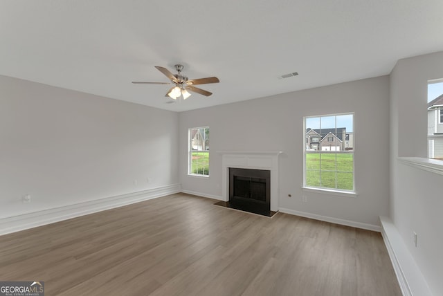 907 Brisley Cir, Hampton, GA 30228 - unfurnished living room with light wood finished floors, plenty of natural light, a fireplace with flush hearth, and ceiling fan