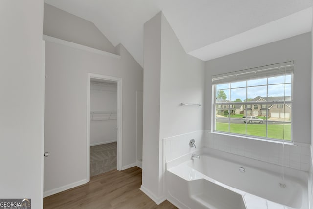907 Brisley Cir, Hampton, GA 30228 - bathroom with vaulted ceiling, a garden tub, a walk in closet, and wood finished floors