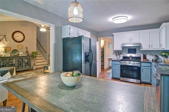 368 Lambeth Dr, Hiram, GA 30141 - kitchen featuring appliances with stainless steel finishes, blue cabinets, under cabinet range hood, white cabinets, and a textured ceiling