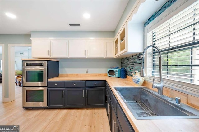 103 Ashley Marsh Dr, Brunswick, GA 31523 - kitchen featuring a sink, stainless steel double oven, white cabinetry, light countertops, and decorative backsplash