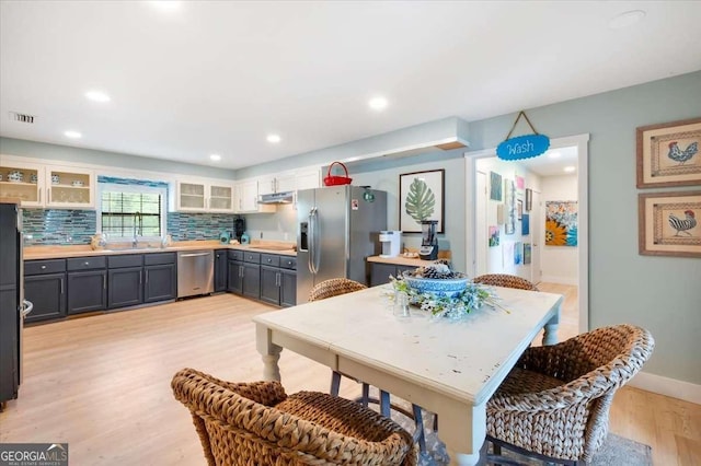 103 Ashley Marsh Dr, Brunswick, GA 31523 - kitchen with appliances with stainless steel finishes, light wood finished floors, tasteful backsplash, glass insert cabinets, and light countertops