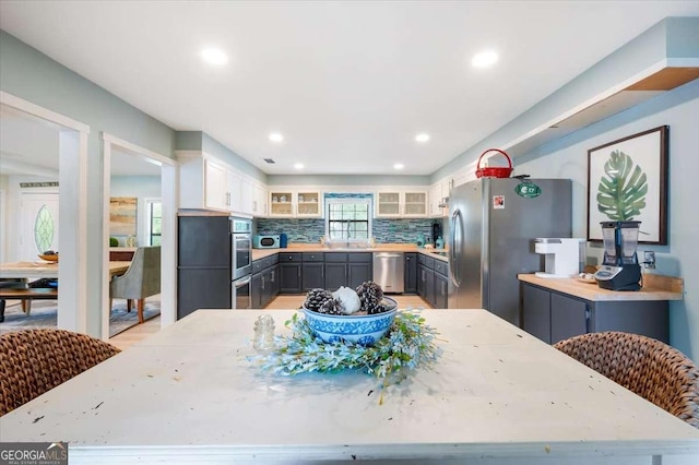 103 Ashley Marsh Dr, Brunswick, GA 31523 - kitchen featuring stainless steel appliances, glass insert cabinets, backsplash, light countertops, and white cabinetry