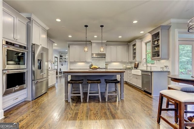 126 Townsend Pass, Alpharetta, GA 30004 - kitchen with appliances with stainless steel finishes, under cabinet range hood, a kitchen island, glass insert cabinets, and a breakfast bar