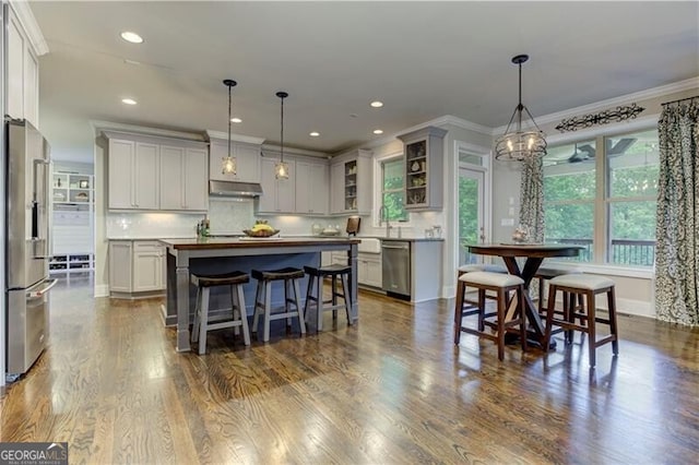 126 Townsend Pass, Alpharetta, GA 30004 - kitchen featuring appliances with stainless steel finishes, under cabinet range hood, a kitchen island, decorative backsplash, and a kitchen breakfast bar