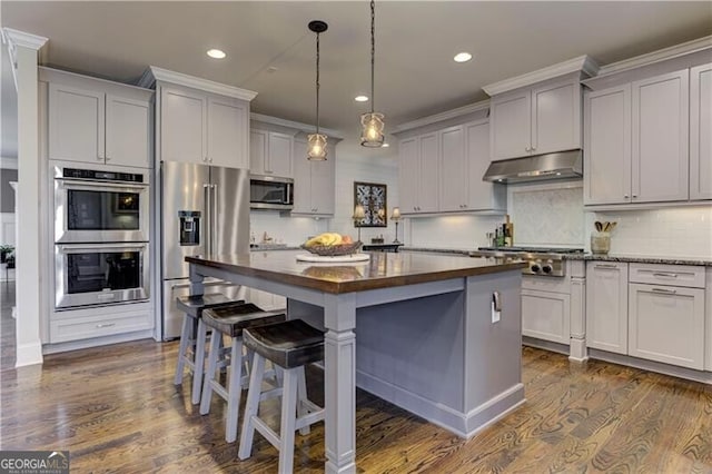126 Townsend Pass, Alpharetta, GA 30004 - kitchen with appliances with stainless steel finishes, under cabinet range hood, a kitchen island, butcher block countertops, and a kitchen breakfast bar
