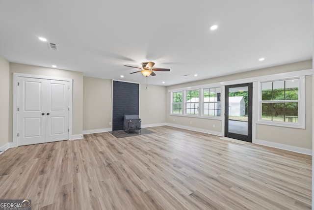 1180 Treadwell Bridge Rd, Statham, GA 30666 - unfurnished living room featuring a wood stove, light wood-type flooring, a ceiling fan, and recessed lighting