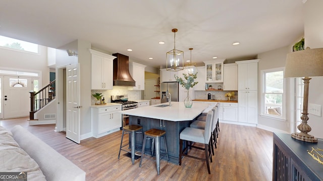 1346 Wind Chime Ct, Lawrenceville, GA 30045 - kitchen featuring custom exhaust hood, appliances with stainless steel finishes, a breakfast bar area, light wood-style floors, and recessed lighting
