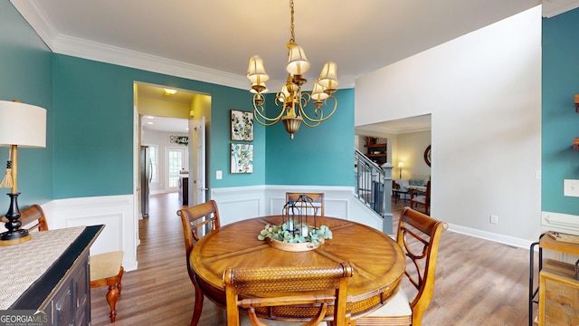 1346 Wind Chime Ct, Lawrenceville, GA 30045 - dining area with stairs, a chandelier, ornamental molding, a wainscoted wall, and wood finished floors