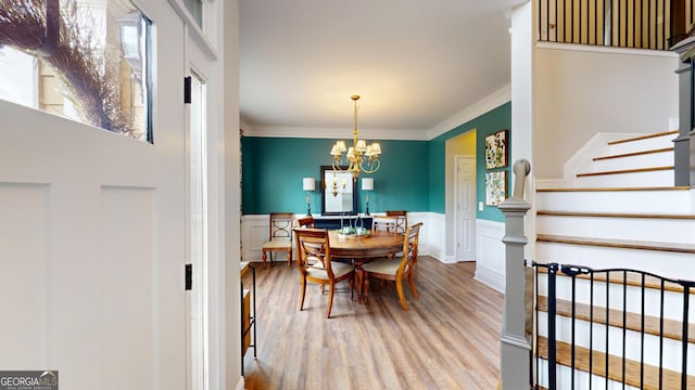 1346 Wind Chime Ct, Lawrenceville, GA 30045 - dining room featuring stairs, wood finished floors, a wainscoted wall, crown molding, and a chandelier