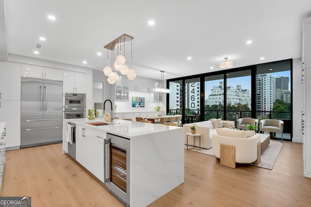 2425 Peachtree Rd NE Unit 902, Atlanta, GA 30305 - kitchen with appliances with stainless steel finishes, beverage cooler, modern cabinets, light wood-style flooring, and white cabinetry
