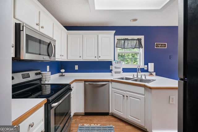 135 Pinewood Cir, Colbert, GA 30628 - kitchen featuring stainless steel appliances, white cabinets, light countertops, light wood-style floors, and a textured ceiling