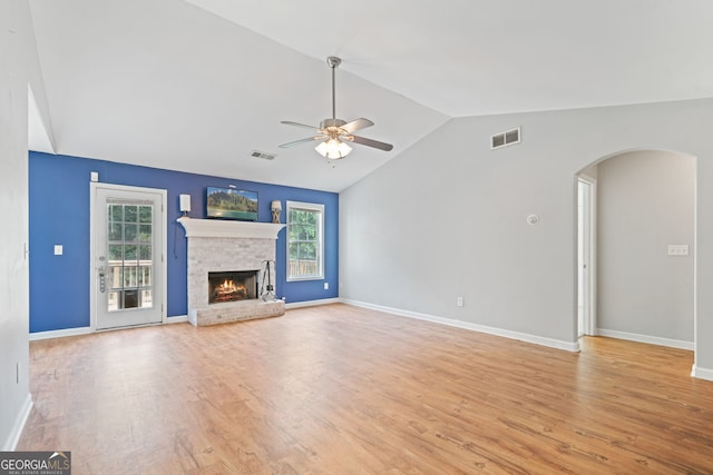 135 Pinewood Cir, Colbert, GA 30628 - unfurnished living room featuring lofted ceiling, ceiling fan, light wood finished floors, a lit fireplace, and arched walkways