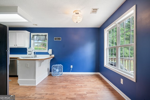 135 Pinewood Cir, Colbert, GA 30628 - kitchen with dishwasher, white cabinets, light wood-style floors, a kitchen bar, and a textured ceiling