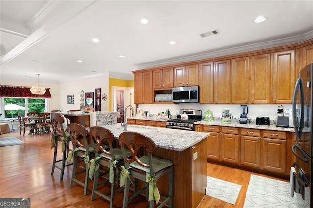 7131 Ridge Rd, Hiram, GA 30141 - kitchen with stainless steel appliances, crown molding, light stone countertops, a breakfast bar area, and brown cabinets