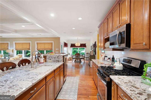 7131 Ridge Rd, Hiram, GA 30141 - kitchen with appliances with stainless steel finishes, brown cabinets, crown molding, light wood finished floors, and decorative backsplash
