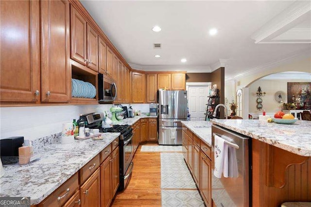 7131 Ridge Rd, Hiram, GA 30141 - kitchen featuring stainless steel appliances, arched walkways, ornamental molding, light stone counters, and light wood finished floors