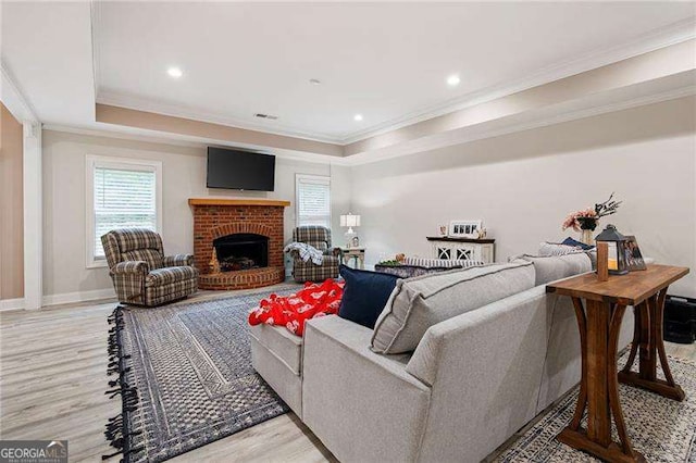 7131 Ridge Rd, Hiram, GA 30141 - living room with a raised ceiling, crown molding, light wood-style floors, a brick fireplace, and recessed lighting