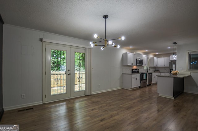 5640 Redan Cir, Stone Mountain, GA 30088 - kitchen featuring stainless steel appliances, a chandelier, a textured ceiling, dark wood-style flooring, and hanging light fixtures