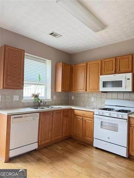 6634 Splashwater Dr, Flowery Branch, GA 30542 - kitchen with white appliances, light wood-type flooring, decorative backsplash, light countertops, and a textured ceiling