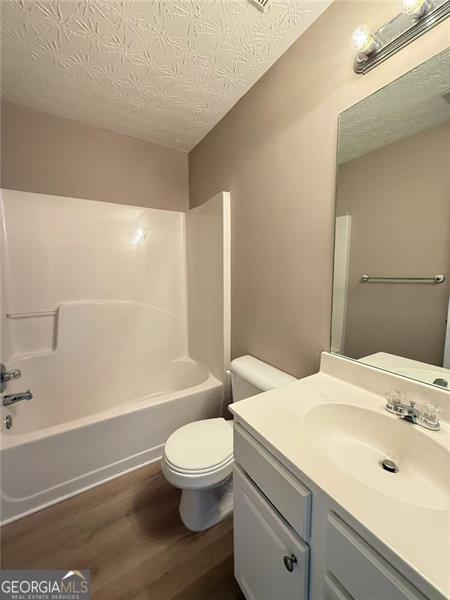 6634 Splashwater Dr, Flowery Branch, GA 30542 - bathroom with wood finished floors, vanity, shower / tub combination, and a textured ceiling