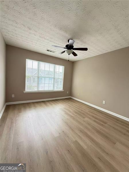 6634 Splashwater Dr, Flowery Branch, GA 30542 - empty room featuring a textured ceiling, wood finished floors, and ceiling fan