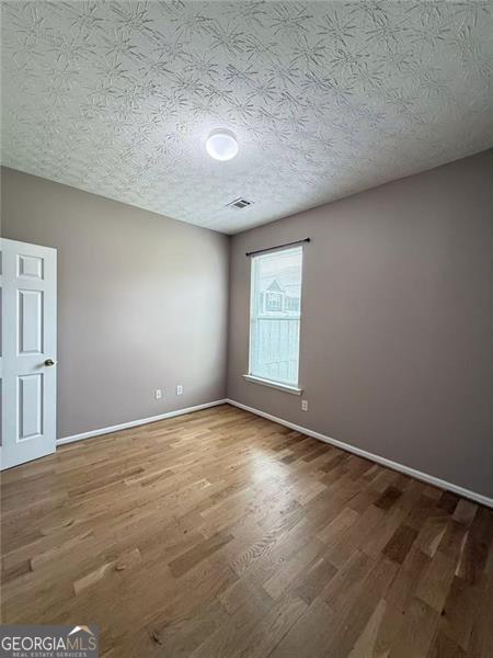 6634 Splashwater Dr, Flowery Branch, GA 30542 - spare room with wood finished floors and a textured ceiling