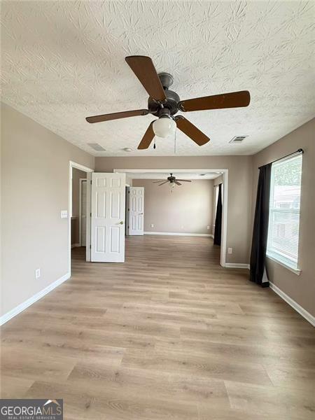 6634 Splashwater Dr, Flowery Branch, GA 30542 - empty room featuring light wood-style floors, a ceiling fan, and a textured ceiling
