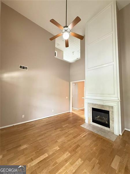 6634 Splashwater Dr, Flowery Branch, GA 30542 - unfurnished living room with high vaulted ceiling, a ceiling fan, wood finished floors, and a tiled fireplace